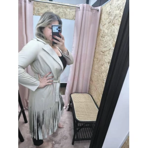 Casaco Franja Rebelde com franjas e polipele, criando um look boho-chic.