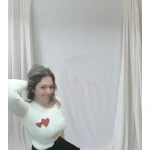 Mulher vestindo camisola feminina com corações, disponível em branco com corações vermelhos e bege com corações dourados.