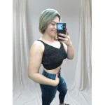 Mulher vestindo um top canelado preto, combinando com jeans rasgado, em pose casual contra fundo neutro.