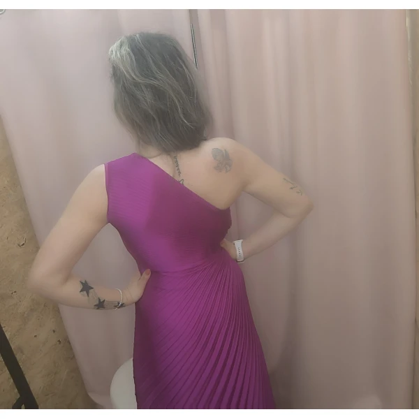 Mulher a usar o vestido Dress Divine Pleats em rosa fúcsia e preto com corte assimétrico e plissado.