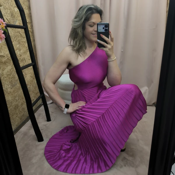 Mulher a usar o vestido Dress Divine Pleats em rosa fúcsia e preto com corte assimétrico e plissado.