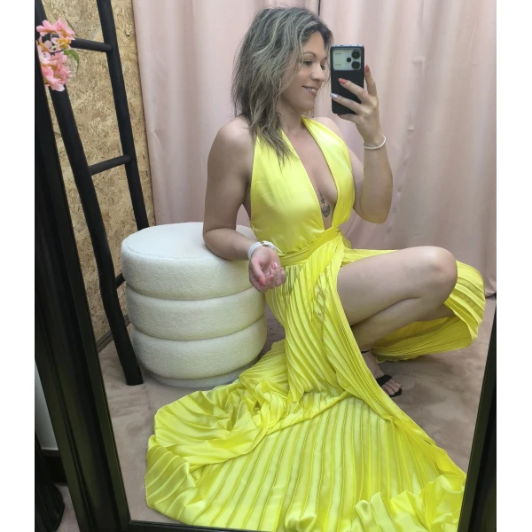 Vestido amarelo plissado com brilho, decote profundo e corte ousado.