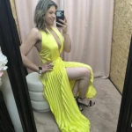 Vestido amarelo plissado com brilho, decote profundo e corte ousado.