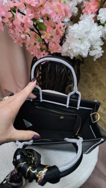Bolsa preta feminina sofisticada com lenço decorativo e alça extra geométrica.